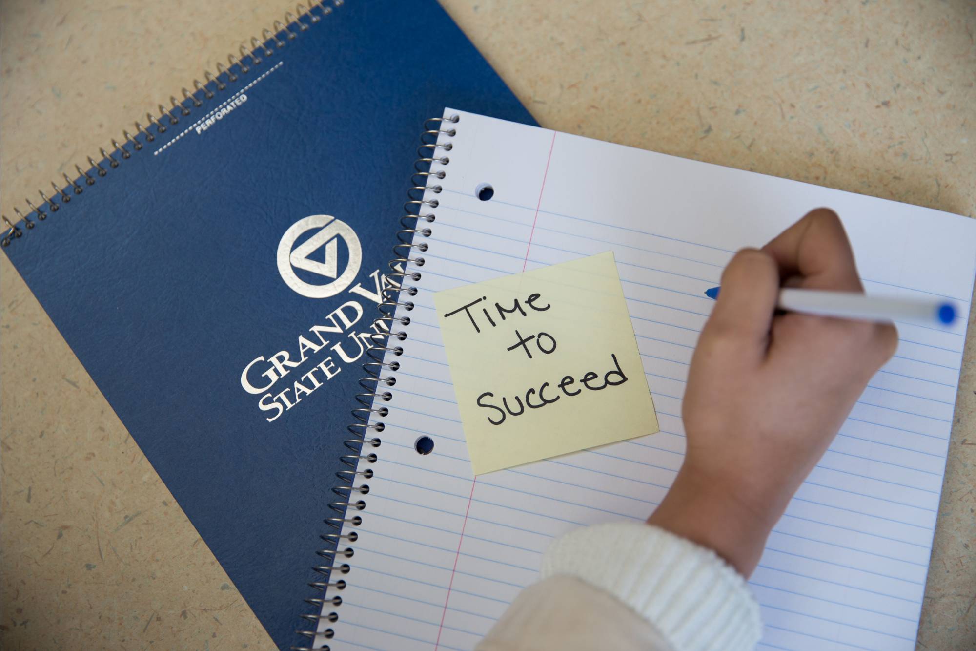 Sticky note with "Time to Succeed" written on it stuck to a blank notebook